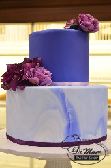 This cake is an absolute statement! A beautiful color tier on top, a marbled tier on the bottom embellished with silk flowers. What&rsquo;s not to love?