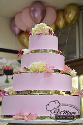 Our four tier smooth cake, is topped with real pink flowers and shimmery gold ribbon. A very classy choice.