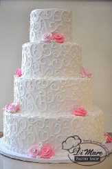 This four tier cream cake accented with white scroll and our pink cream flowers for a pop of color.