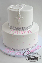 2 Tier with Rosary. A delicately drawn rosary tops this two tier whipped cream cake along with diamond ribbon and swiss dots on the bottom tier- a great addition for a religious ceremony.
