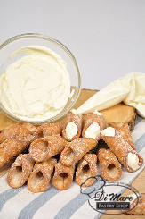 Our signature miniature cannoli &ndash; a fried dough with our delicious cannoli filling filled fresh daily