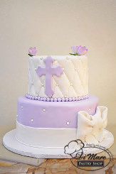This rolled fondant two tier cake would complete any Communion celebration. The bottom lavender tier is embellished with white pearls and a white rolled fondant pin cushion design adorned with a lavender cross and gum paste flowers on top.