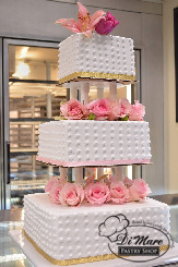 Smooth swiss dots topped with beautiful pink flowers, this cake will be the center of attention at any wedding.