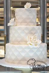 An ornate 3 tier fondant cake, designed meticulously designed with triangles and gum paste flowers.