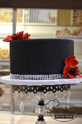 A textured, black cake with red flowers; a new trendy cake style.