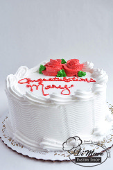 A simple whipped cream cake with beautiful flowers and a congratulatory message.