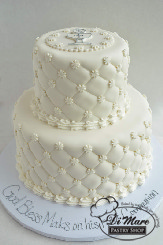 A two tier fondant cake with a fondant chalice on top and a quilted pattern around both tiers of the cake.