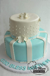 Blue fondant with white stripes adornes the bottom of this two tier cake while white fondant and swiss dots completes the top of this beautiful religious cake.