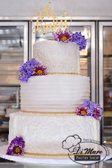 Whipped cream lace decorations adorn the top and bottom tier of this cake, with a simple spoon effect for the middle tier. Fresh flowers and a loving cake topper finish garnish this beautiful cake.