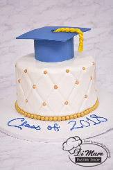 Blue and gold fondant pin cushion cake finished off with a graduation cap.