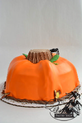 A beautiful smooth fondant cake in the shape of a pumpkin with a wonderfully textured stem.